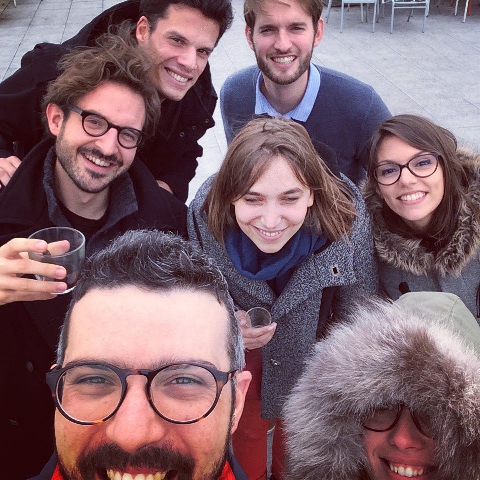 7 personnes souriantes qui posent face à l'appareil photo avec des cafés en main.
