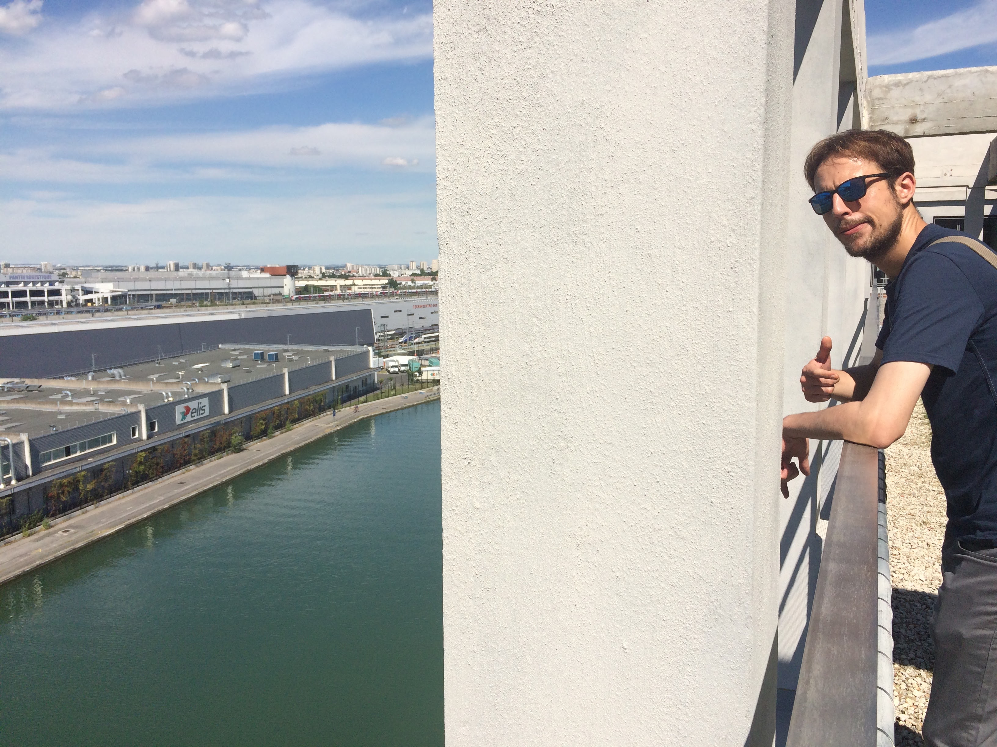 Florent qui regarde la caméra en me faisant signe, sur le rooftop de Pantin