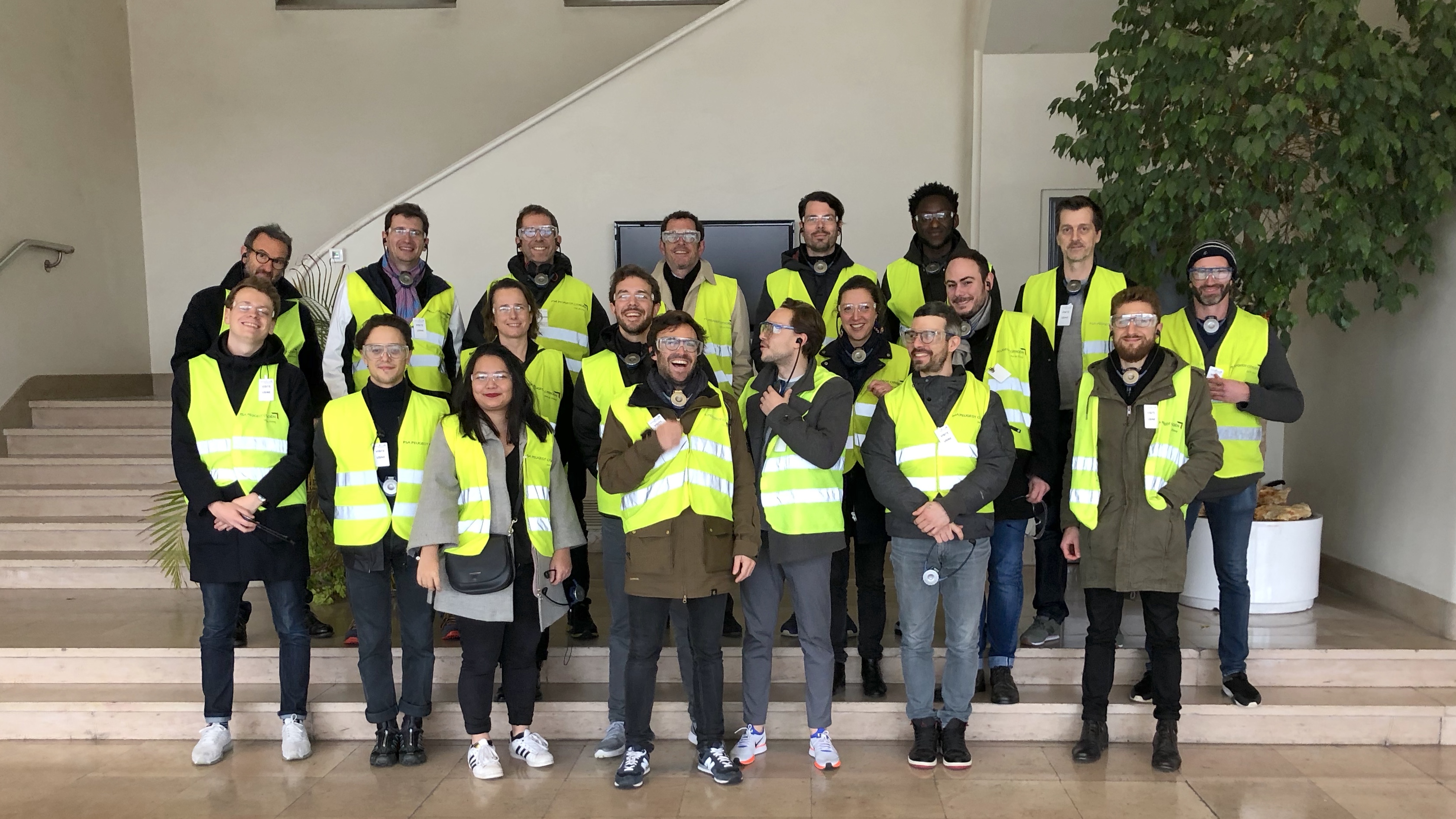 l'équipe en pose dnas l'entrée de l'usine, avec des gilets jaunes fluo et des lunettes de protection.