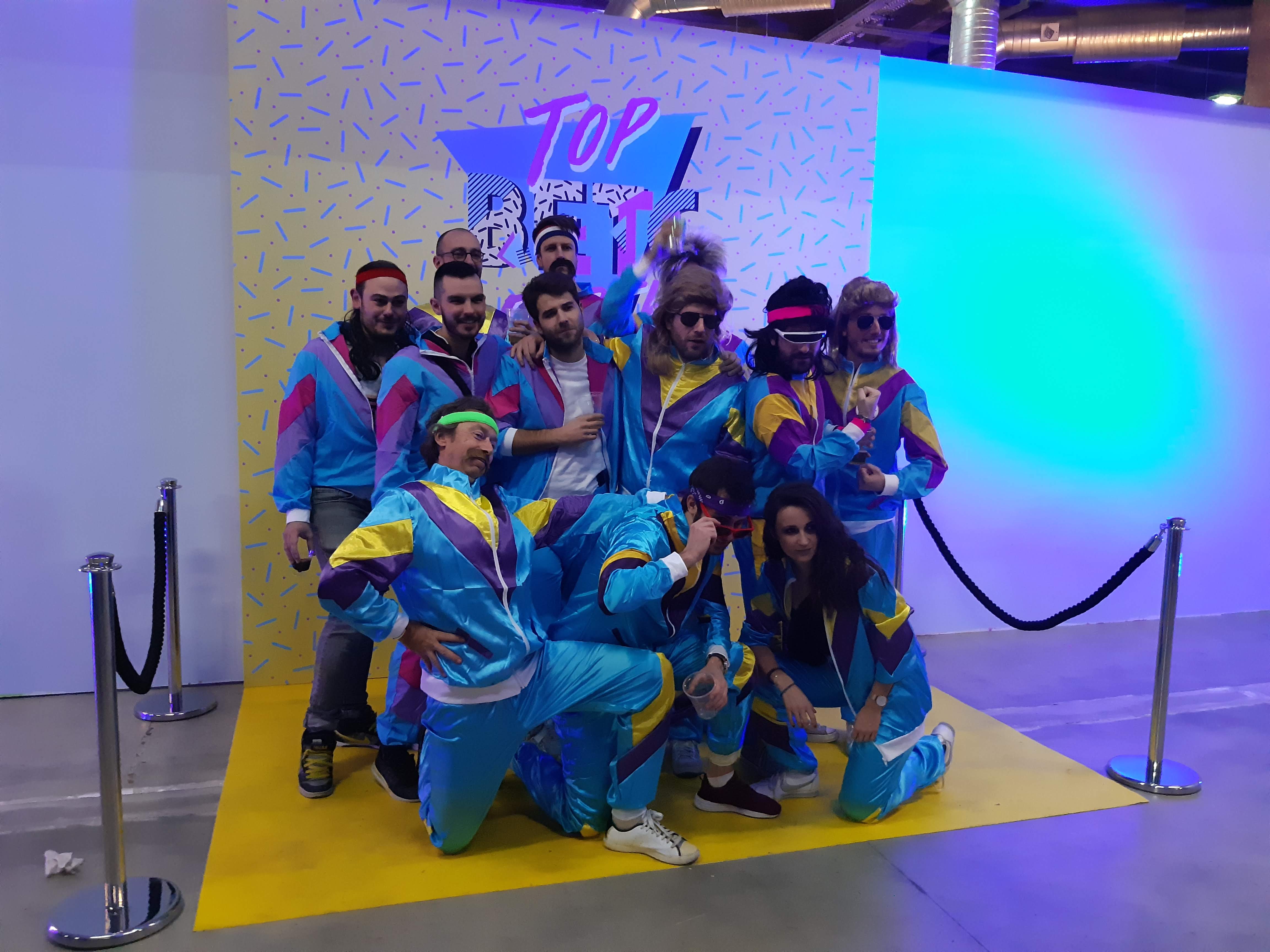 Équipe attablée dans un café lumineux, souriant à l’appareil photo lors d’un déjeuner.