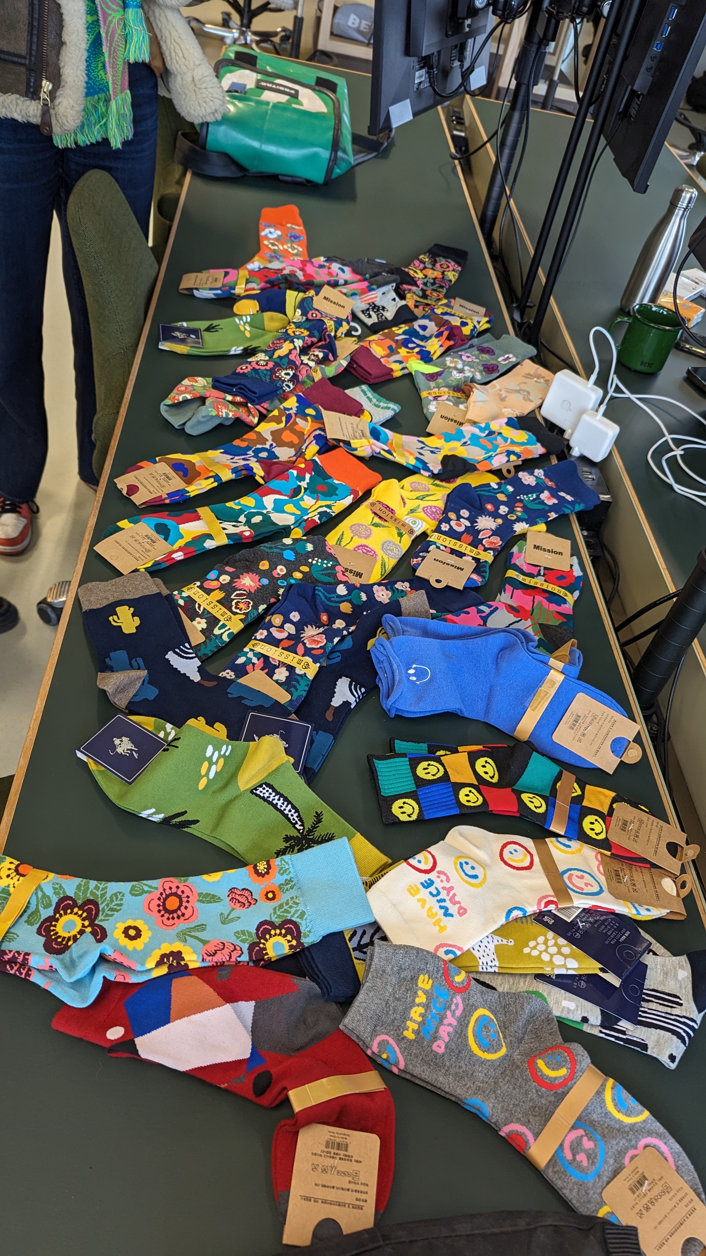 Table de bureau recouverte de chaussettes colorées aux motifs variés, disposées en éventail.