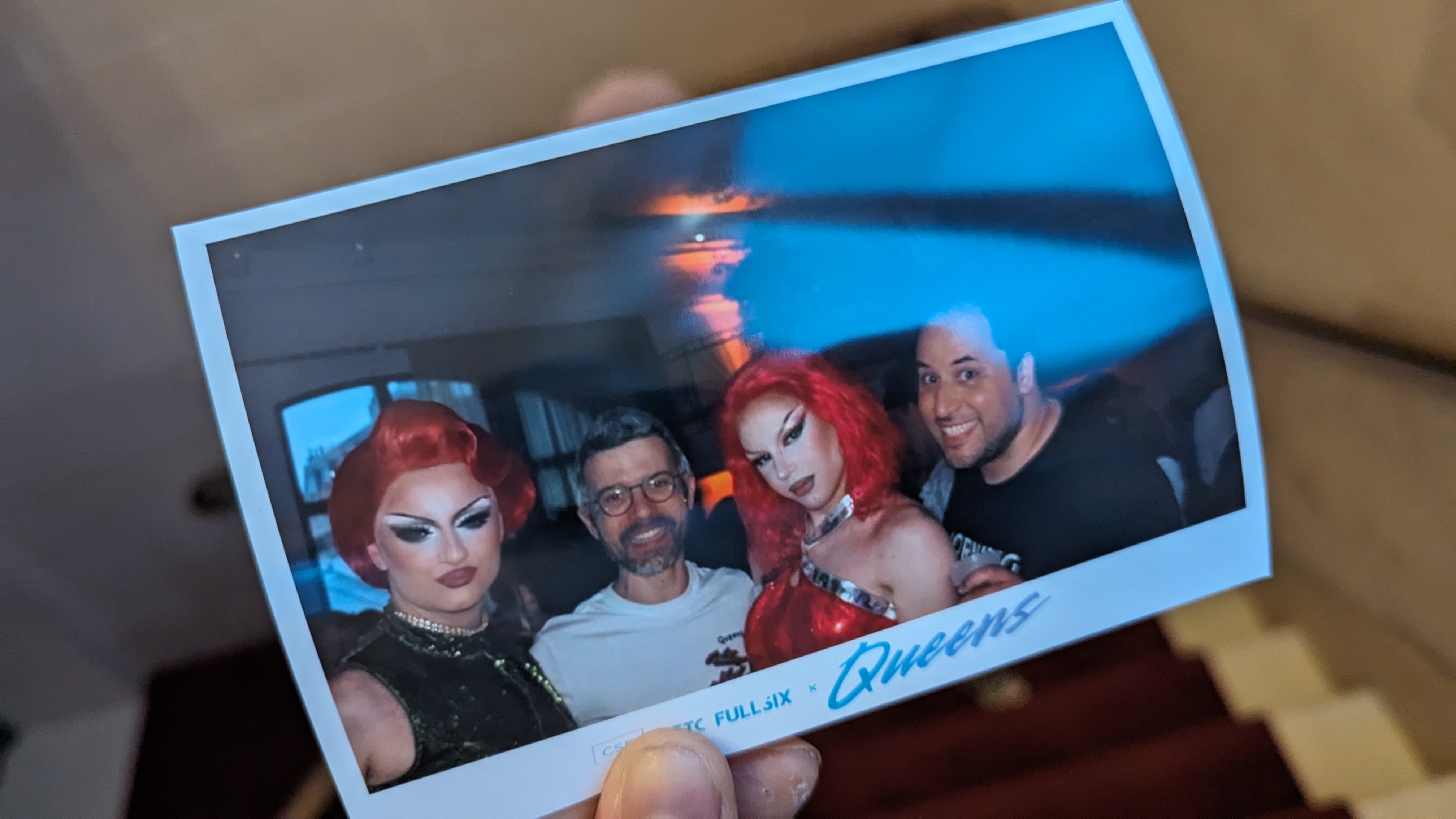 Photo souvenir tenue à la main montrant quatre personnes déguisées lors d’une soirée “Queens”.