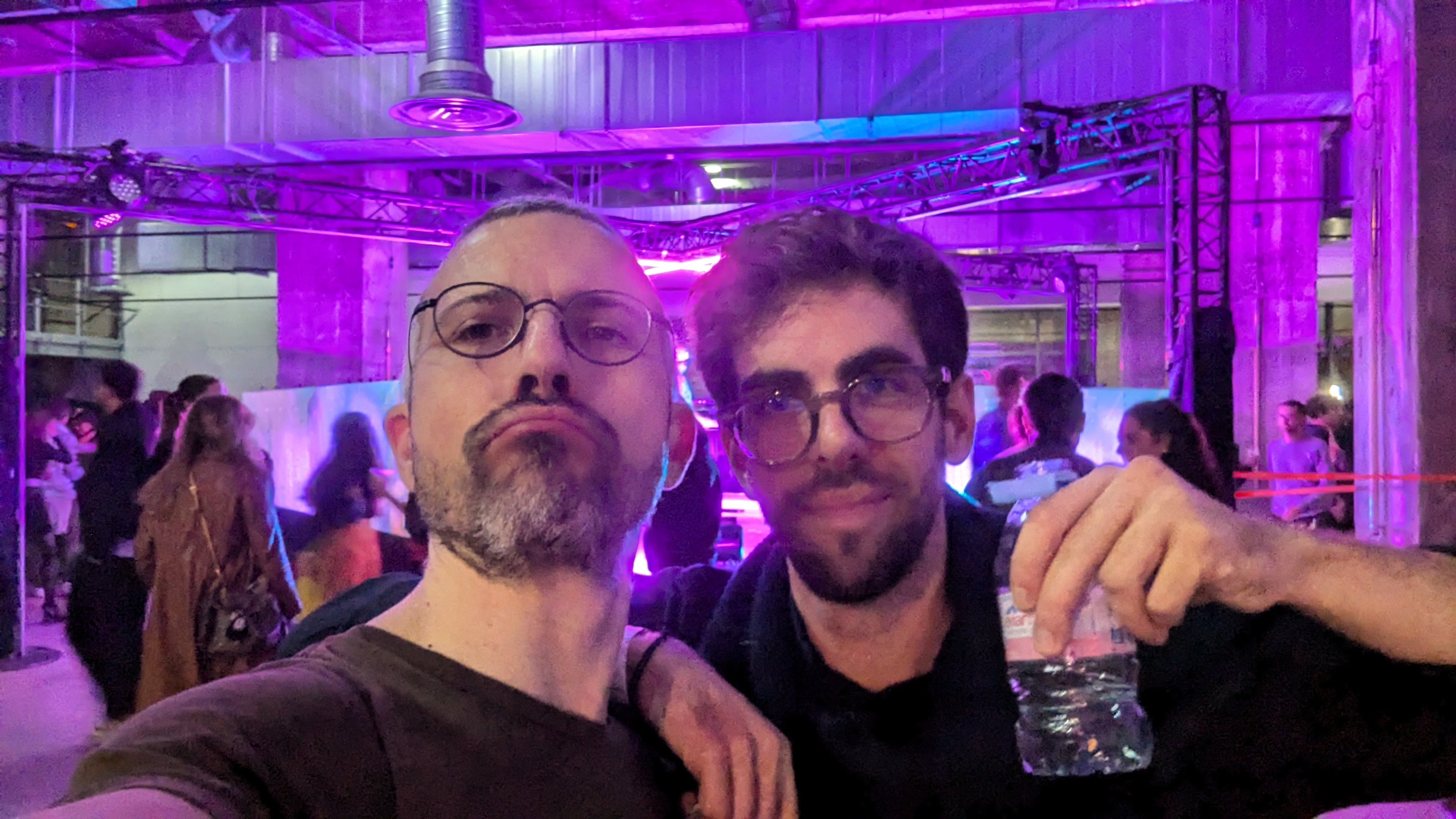 Deux collègues posant lors d’un événement avec éclairage violet et ambiance festive.