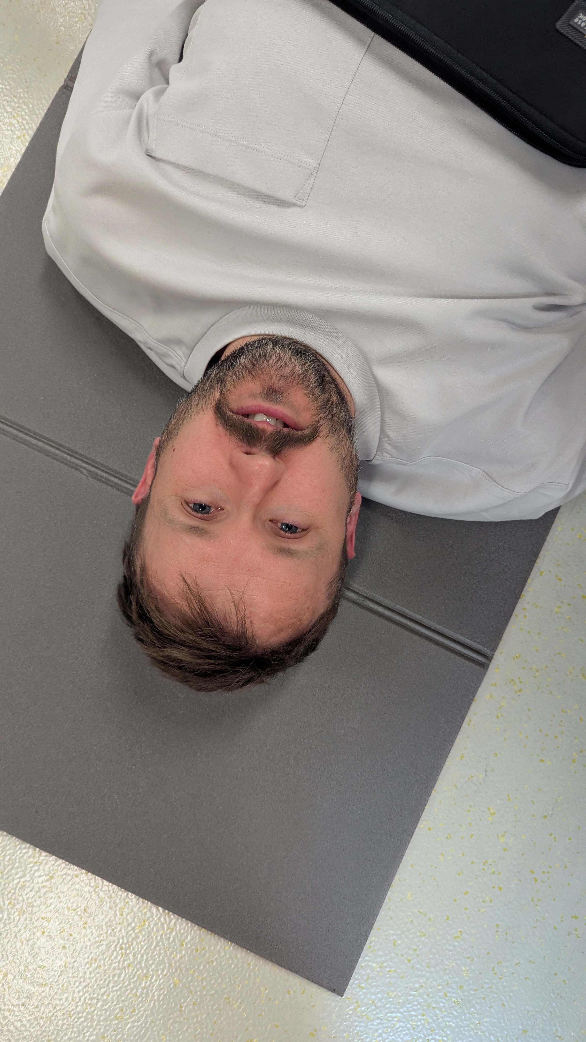 Portrait d’un homme allongé au sol, tête inclinée, regardant l’objectif.